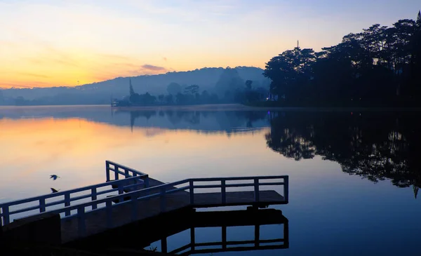 Kleine Brücke spiegelt sich bei Sonnenaufgang auf dem See — Stockfoto