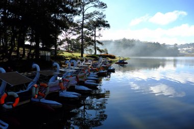 Ördek tekne, araç taşıma grup ve turizm için su sakin ol, yüzey suyu daha Tho Gölü, bir hedef için seyahat çam ormanları arasında Da Lat city, Vietnam, gölde yansıtmak