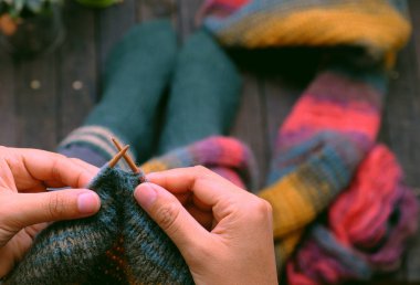 Top view woman sitting at home balcony, knit colorful wool scarf