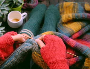 Top view woman sitting at home balcony, knit colorful wool scarf