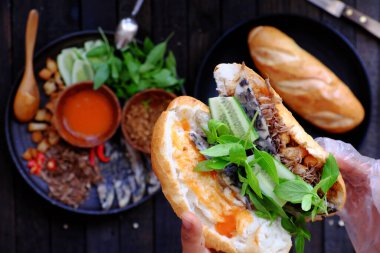 Close up from high view woman hand prepare breakfast, Vietnamese vegan bread stuff with mushroom pie, tomato sauce, herb, fried chopped breads, tofu, shredded vegetables, a popular Vietnam food