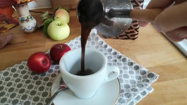 コーヒーは沸騰させずにストーブの上のトルコで醸造されます 白杯に熱々の淹れたてのコーヒーを注ぐ 地上コーヒー ホットドリンク おはようございますコーヒーから — ストック動画