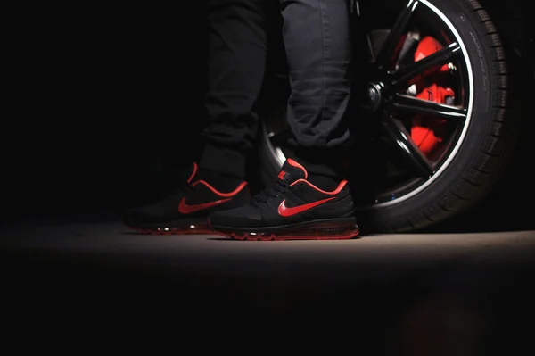 Un hombre con zapatos deportivos Nike Air Max 2017 perfectos disparó cerca del coche Mercedez Benz sobre fondo oscuro. Concepto de deporte y calzado casual. Krasnoyarsk, Rusia - 10 de enero de 2018 —  Fotos de Stock