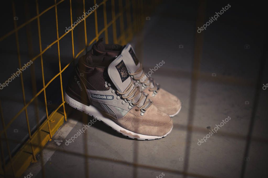 Zapatillas Reebok GL 6000 Mid de color beige marrón sobre fondo industrial oscuro. Imagen ilustrativa editorial de cerca de los zapatos deportivos disparados en Krasnoyarsk, Rusia - 10 de enero de