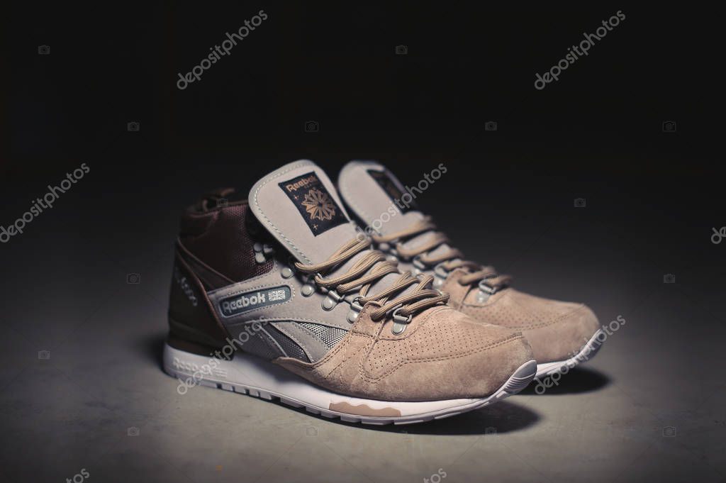 Zapatillas Reebok GL 6000 Mid de color beige gris marrón sobre fondo industrial oscuro. Imagen ilustrativa editorial de cerca de los zapatos deportivos disparados en Krasnoyarsk, Rusia - de enero de 2018 2023