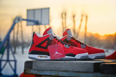 Nike Air Jordan IV Retro basketball shoes in fire red, cement grey and black colors shot outdoors at the basketball court background. Krasnoyarsk, Russia - February 7, 2015 clipart