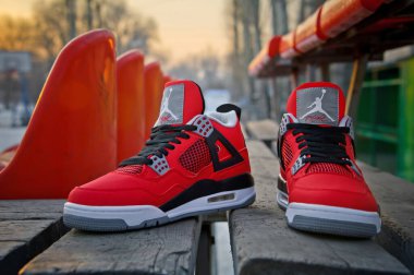 Perfect Nike Air Jordan IV Retro sneakers in fire red, cement grey and black colors shot outdoors at colorful background. Detailed view of shoes by famous brand. Krasnoyarsk, Russia - February 7, 2015 clipart
