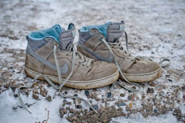 Eski ve kirli Nike 6.0 Sunk High Lr spor ayakkabıları. Karla kaplı asfalt yolda bırakılmış bağcıksız spor ayakkabılar. Krasnoyarsk, Rusya - 21 Kasım 2014