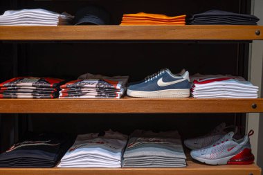 Ahşap raflarda katlanmış tişörtler ve spor ayakkabılar. Nike Hava Kuvvetleri 1-1 ve Air Max 270 spor ayakkabıları. Rusya 'nın Krasnoyarsk kentindeki Nike mağazasında yeni moda kıyafetler sergilendi - 3 Haziran 2019