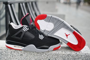 Nike Air Jordan IV Retro marka kırmızı, çimento gri ve siyah renkli basketbol ayakkabıları soyut kentsel arka planda çekildi. Krasnoyarsk, Rusya - 16 Nisan 2015