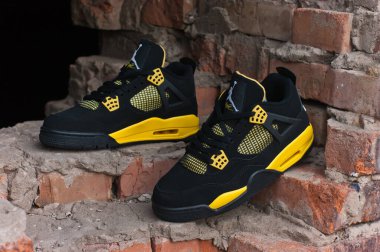Nike Air Jordan IV 4 Retro basketball shoes in yellow and black colorway shot outdoors on an old red brick background. Krasnoyarsk, Russia - February 11, 2015 clipart