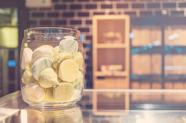 Pastel colored meringues in a glass jar at pastry shop, blured background, copyspace.