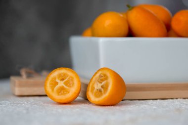 Pembe arka planda bir kupada kumkuat, asitli.