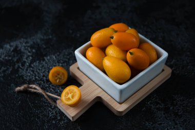 Siyah arkaplanda meyve kumkatını kes, turunçgiller