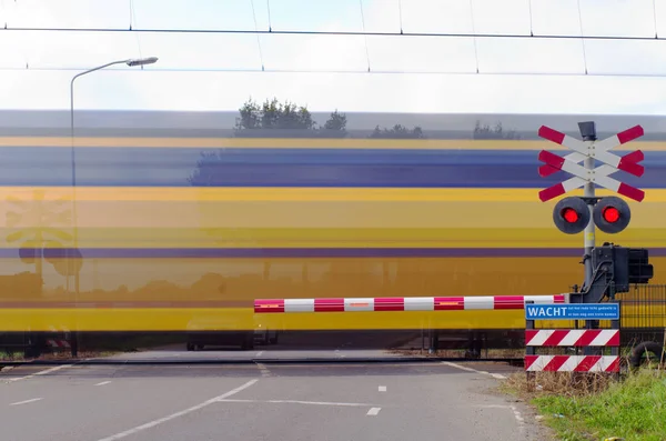 Nederlandse trein die een spoorwegovergang passeert wazig door beweging — Stockfoto
