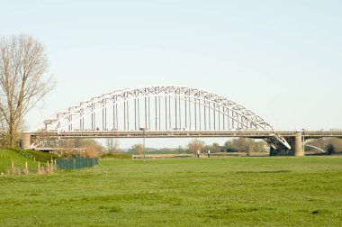 Waalbrug, Hollanda, Nijmegen 'de ön planda bir çayır bulunan Waal Nehri' nin üzerinde.