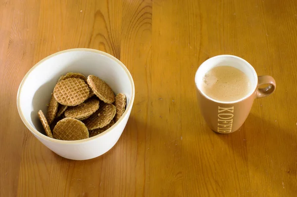 木製のテーブルの上にミニストロッパウェルスとコーヒーカップのボウル ストロップワッフルは伝統的なオランダのクッキーです Koffieとはコーヒーを意味する — ストック写真