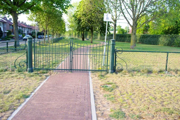 Closed metal gate that gives access to dog walking area next to a residential area in Elst, Netherlands