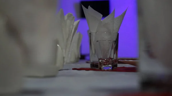 Restorandaki servis masası. Kırmızı bir masa örtüsü ve çok renkli duvarlarda beyaz peçeteler şarap bardakları.