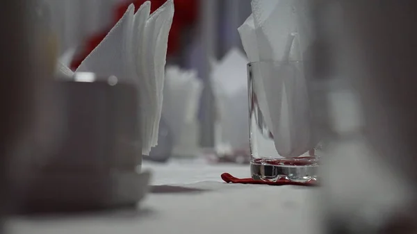 Restorandaki servis masası. Kırmızı bir masa örtüsü ve çok renkli duvarlarda beyaz peçeteler şarap bardakları.