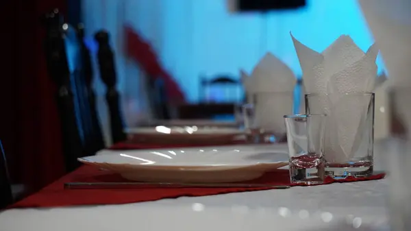 Restorandaki servis masası. Kırmızı bir masa örtüsü ve çok renkli duvarlarda beyaz peçeteler şarap bardakları.