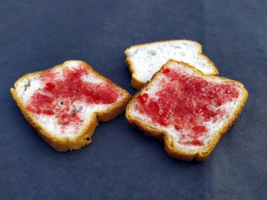 Pürüzsüz arka planda kırmızı reçelli beyaz taze ekmek.