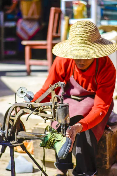 Arbeiter reparieren Schuhe mit traditioneller Maschine in der Yuanyang Straße in Yuanyang, China. — Stockfoto