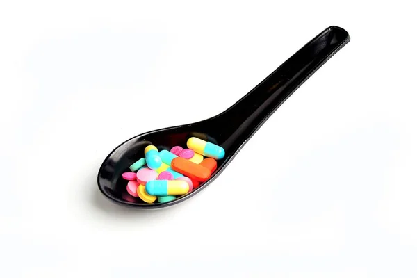 Colorful pills on ceramic spoon — Stock Photo, Image