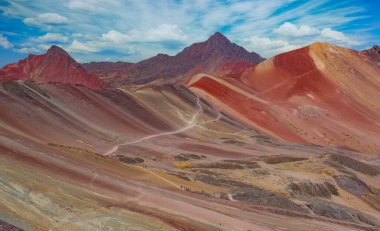 Vinicunca Vadisi 'ndeki Gökkuşağı Dağı' nda yürüyüş manzarası. Apu Ausangate arkada. Tüm kayalar, dağlar ve kum kırmızı renkler tarafından istila edilir. Cusco Bölgesi, Peru