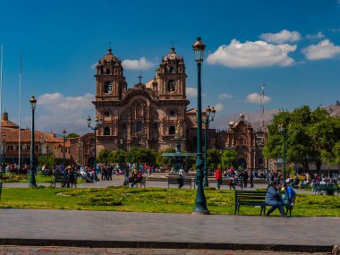 İnsanlar sabahın erken saatlerinde ana meydanda yürüyorlar. Cizvit Kilisesi cephesi (İsa Cemiyeti Kilisesi). Cusco Şehri, Peru