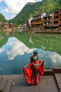 Yerel etnik kökenden geleneksel Çin kostümleri. Çift, Çin 'in Hunan bölgesindeki Fenghuang Antik Kasabası' nda Tuojiang Nehri 'nin önünde pozlar veriyor. 