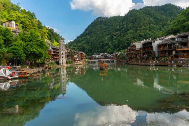 Wanmingta Pagoda ve arka planda köprü olan eski kasabanın panoramik manzarası. Yeşil su, Çin 'in Hunan bölgesindeki Fenghuang Antik Kasabası' ndaki manzarayı yansıtıyor.
