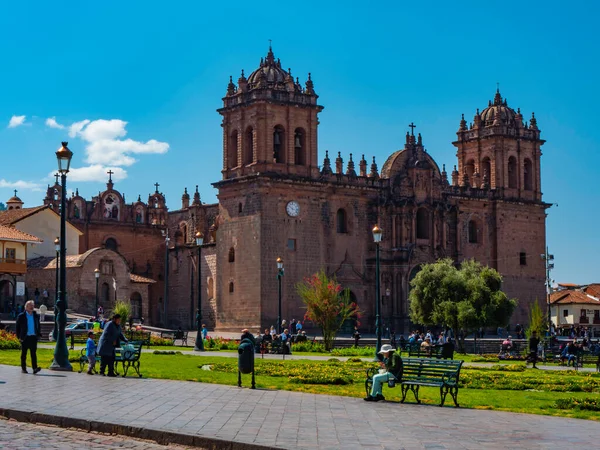 İnsanlar sabahın erken saatlerinde ana meydanda yürüyorlar. Barok tarzında katedralin yan görüntüsü. Cusco Şehri, Peru 