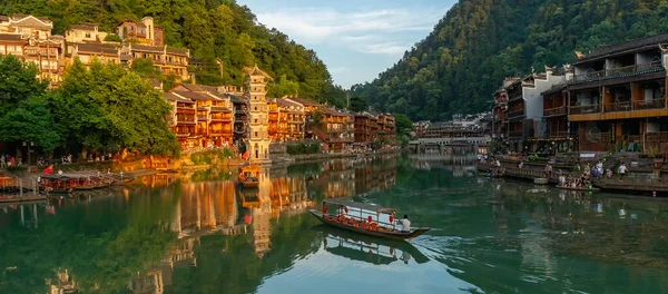 Otantik bir Çin manzarasının resimli manzarası. Geleneksel tekne Tuojiang Nehri 'nin sularında eski Wanmingta Pagoda, eski ahşap evler ile yol alır. Fenghuang Eski Şehir, Çin