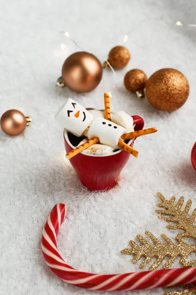 Funny winter holidays concept. Happy and joyful snowman from marshmallows lies in a red cup of coffee or cocoa, as it were in the bath, enjoying the Christmas atmosphere — Stock Photo, Image