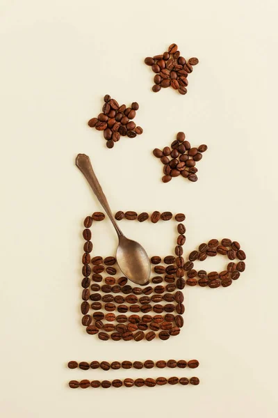 Kreatywne płaskie ułożenie filiżanki lub kubka gorącej kawy wyłożonej paloną ziarnem kawy z brązem lub metalową łyżką wewnątrz na pastelowym tle. Kawa w kształcie gwiazdy w pobliżu — Zdjęcie stockowe