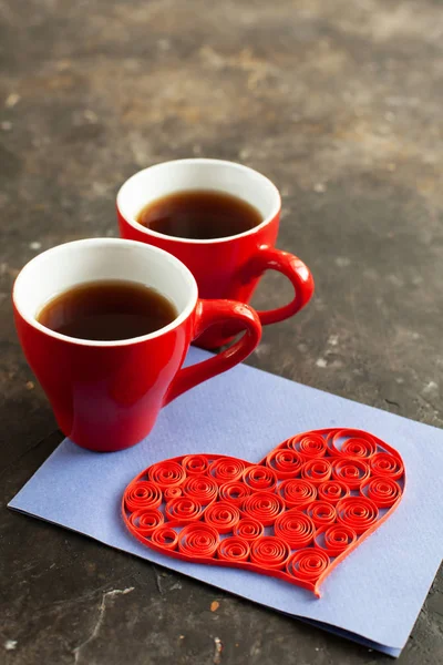 Koyu beton arka planda tüy dökme tekniğini kullanan iki bardak espresso, kahve ve el yapımı kalp kartpostalları. Sevgililer Günü için içki ve sürprizle romantik randevu fikri. Kapatın. - Stok İmaj