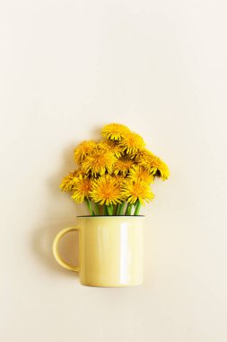 Anneler günü ya da doğum günü tebrik kartı tasarımı, mesaj için boş yer. Pastel bej arka planda açık sarı fincanda parlak sarı karahindiba çiçekleri. Yaratıcı çiçekli minimalist durgun hayat, düz uzanma