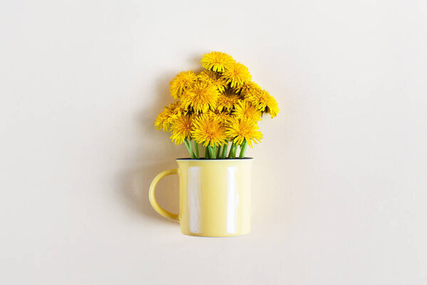 Mother day or birthday greeting card design, free space for text. Bouquet of bright yellow dandelion flowers in light yellow mug on pastel beige background. Creative floral minimalistic still life, flat lay