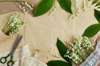 Vadi arka planının güzel zambakları. Bahçe zambakları waffle külahı ve zarf içinde, yapraklar, dantel, makas ve el işi kağıdında tüy. Metin için boş yer, düz yatak. Çiçek çerçeveli kart tasarımı