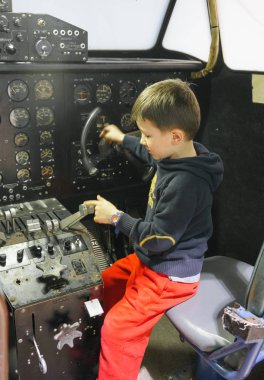 Young boy in cockpit of stationary aeroplane 