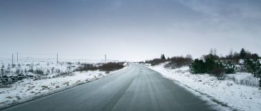 Kasvetli karlı manzara, yol ve fırtınalı gökyüzü