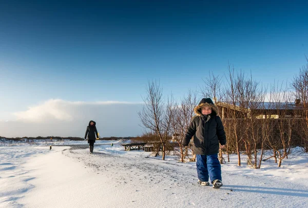 Mother and son walking in snow covered landscape