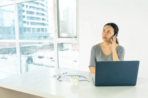 Mujer con portátil usando el teléfono móvil — Foto de Stock