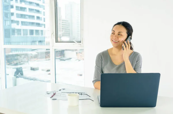 Mujer con portátil usando el teléfono móvil — Foto de Stock