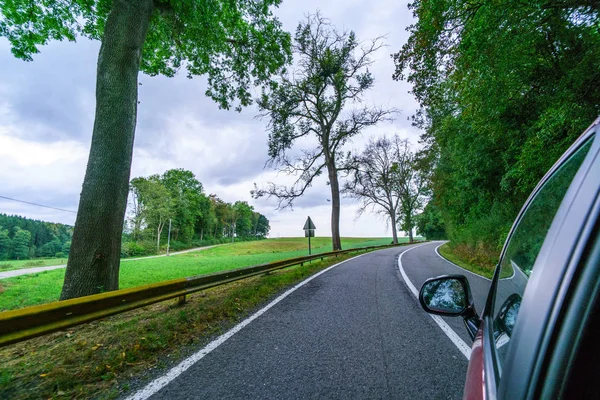 Coche conduciendo por un camino rural vacío con árboles al borde — Foto de Stock