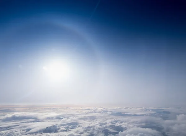 Halo solar, resplandor solar y cielo azul por encima del paisaje nublado — Foto de Stock