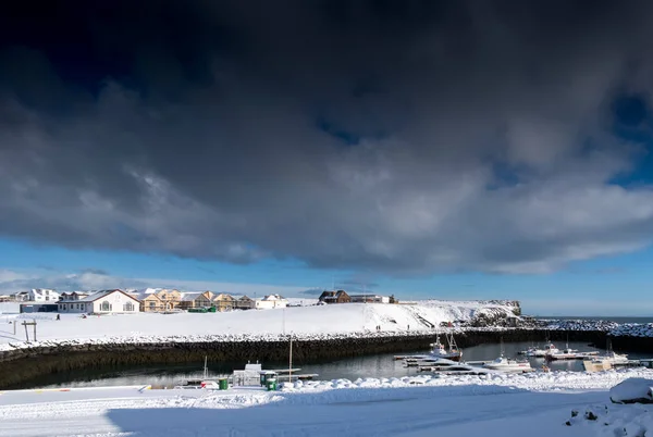 Pequeños edificios de la ciudad y barcos en nieve y cielo tormentoso — Foto de Stock