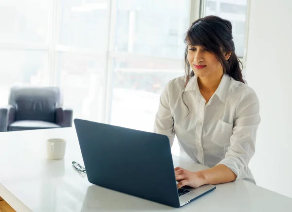 Mujer joven usando el ordenador portátil en el escritorio — Foto de Stock