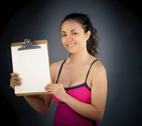 Woman looking at camera holding clipboard — Stock Photo, Image